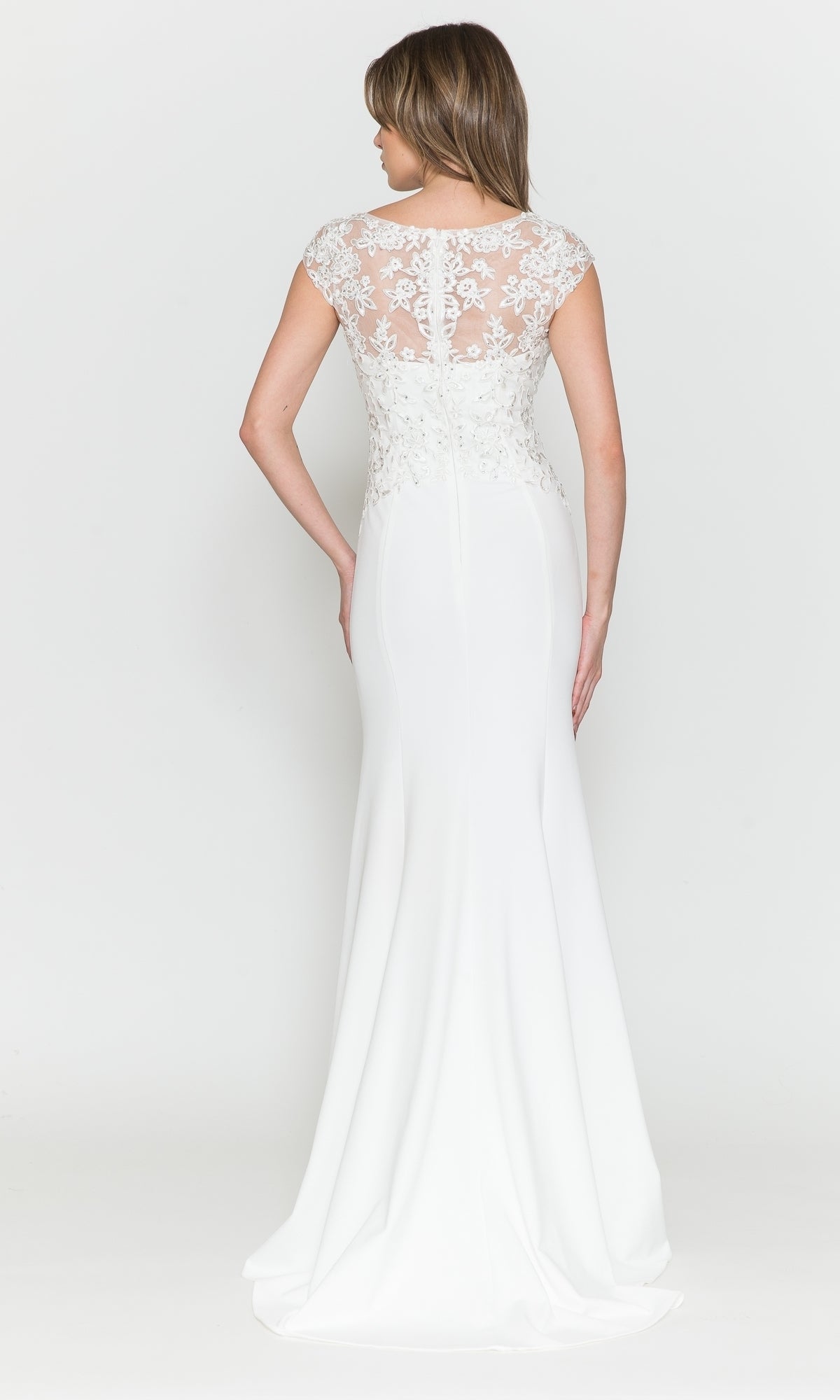 A woman stands with her back to the camera against a plain background, wearing the Cap-Sleeve Embroidered Jersey Long Prom Dress 8558, featuring a white fitted silhouette, cap sleeves, and a sheer lace back.